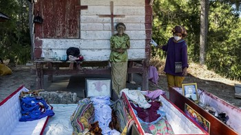 A relative stands next to the remains of Sanda after they are removed from the burial chamber during Ma'nene, a Torajan ritual where families exhume, clean and redress their deceased relatives to honour them, in Pangala, North Toraja, South Sulawesi