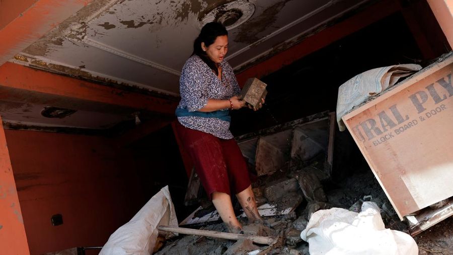 Seorang wanita menyelamatkan celengan di rumahnya yang rusak akibat banjir bandang dan tanah longsor di Trishuli, distrik Nuwakot, Nepal, pada 28 Agustus 2026.