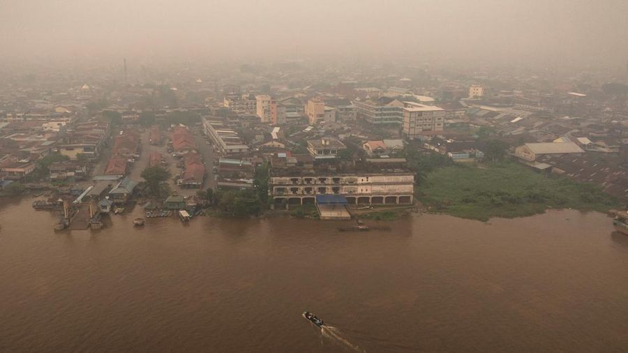 Tampilan dari drone memperlihatkan orang-orang menaiki perahu kayu menyeberangi Sungai Kapuas saat kabut asap akibat kebakaran rimba menyelimuti wilayah tersebut di Pontianak, Provinsi Kalimantan Barat, Indonesia, pada 27 Agustus 2026.