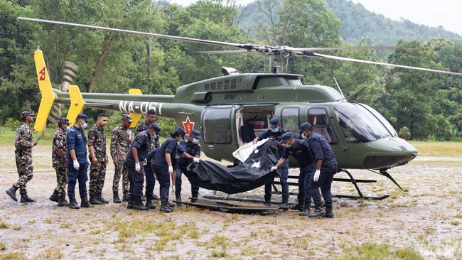 Nepali Army personnel disembark a helicopter carrying bodies of deceased victims during rescue operations after flash floods, at Trishuli camp in Nepal's Nuwakot district on August 28, 2026. More than 1,400 people are missing and at least 552 have be