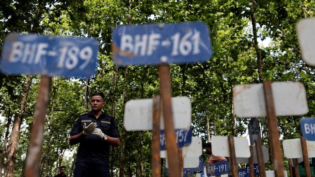 A police officer stands near identification number tags for bodies at the Devghat mass burial site for victims of deadly flash floods and mudslides, in Chitwan, Nepal, August 30, 2026. REUTERS/Navesh Chitrakar