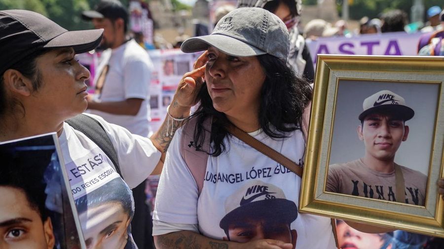 Seorang wanita menenangkan wanita lain nan sedang memegang foto orang lenyap dalam sebuah unjuk rasa untuk memperingati Hari Internasional Korban Penghilangan Paksa di Mexico City, Meksiko, pada 30 Agustus 2026.