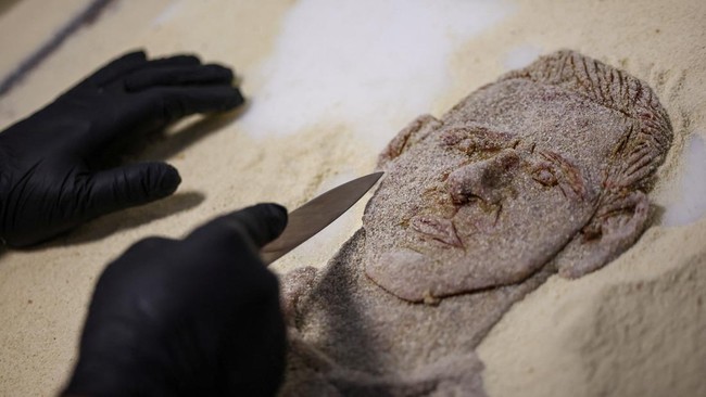 Chef Damian Zanotti, who works at the restaurant El Antojo, prepares a schnitzel, known as milanesa in Argentina, with the face of Argentina's soccer legend Lionel Messi, a day after he announced his retirement from the national team, in Buenos Aires