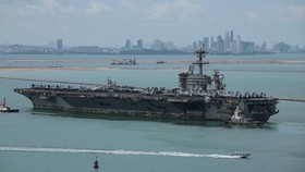 The U.S. Navy Nimitz-class aircraft carrier USS Abraham Lincoln sails toward Laem Chabang Port before docking for a rest stop following a long deployment in the Middle East, with the Pattaya skyline in backdrop, in Chonburi province, Thailand, Septem