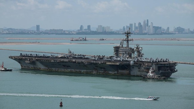 The U.S. Navy Nimitz-class aircraft carrier USS Abraham Lincoln sails toward Laem Chabang Port before docking for a rest stop following a long deployment in the Middle East, with the Pattaya skyline in backdrop, in Chonburi province, Thailand, Septem