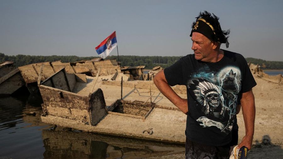 Zoran Lovric, seorang nelayan setempat, berdiri di dekat buntang kapal perang Jerman dari Perang Dunia II nan muncul ke permukaan akibat surutnya air Sungai Danube—yang disebabkan oleh kekeringan dan suhu panas ekstrem—di dekat Prahovo, Serbia, pada 13 Agustus 2026.