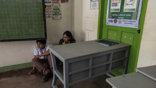 A teacher gestures for silence as she and a student take cover during an active-shooter drill following recent school shootings in the country, at Carlos F. Gonzales High School in San Rafael, Bulacan, Philippines, September 3, 2026. REUTERS/Eloisa L