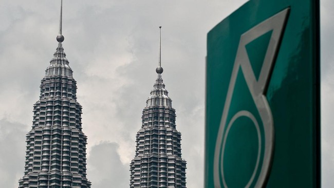 Malaysia's iconic Twin Towers are seen in the background of the Malaysian oil and gas company Petronas logo at a petrol station in Kuala Lumpur on August 13, 2014. Malaysian state energy firm Petronas is expected to announce its second quarter earnin