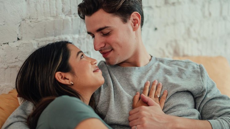 Affectionate young couple embracing at home&comma; smiling and looking into each other's eyes&comma; showing love and connection