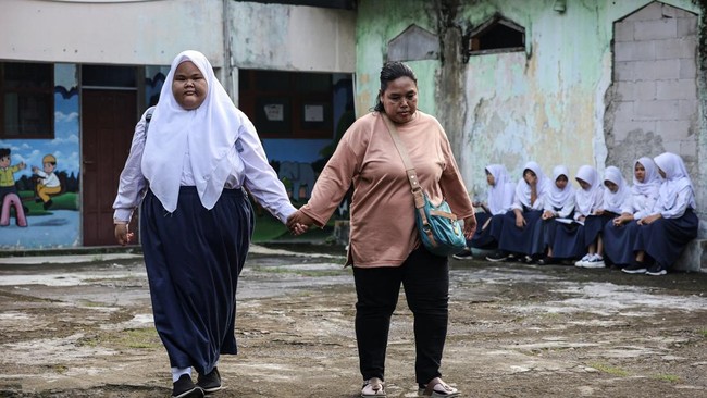 Intan Permatasari, 14, walks with her mother at a trial visit of a junior high school, ahead of her full-time return in August, in Bogor, West Java province, Indonesia, May 13, 2026. Bullied relentlessly by classmates as her struggles with obesity in