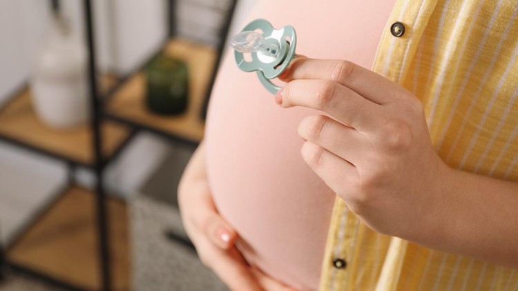 Pregnant woman with pacifier at home&comma; closeup