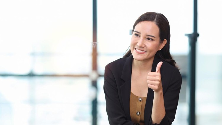 Portrait of confident young asian businesswoman sitting and showing thumb up with happy smiling face emotion while holding smart mobile phone and looking at camera&comma; blur building city background