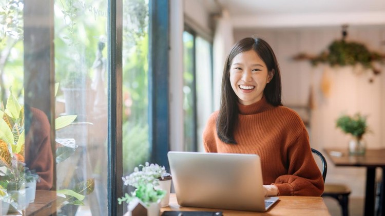 Happy young Asian girl working at a coffee shop with a laptop