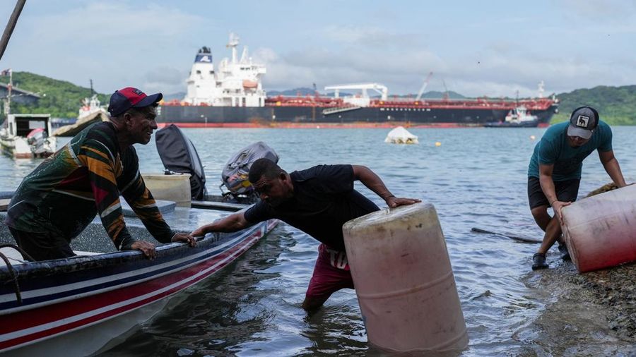 Para nelayan dari pelabuhan La Boca memuat tangki bensin ke atas perahu saat kapal berbendera Liberia, MSC ILLINOIS VII, melintasi Terusan Panama di tengah penurunan permukaan air akibat kurangnya curah hujan nan mengenai dengan El Nio, di Panama Cit
