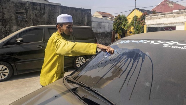 A man clears volcanic ash from his car windscreen following the eruption of Mount Anak Krakatoa in Bogor, West Java on September 6, 2026. Mount Anak Krakatoa erupted on September 5, producing a fountain of lava and booming sounds that could be heard