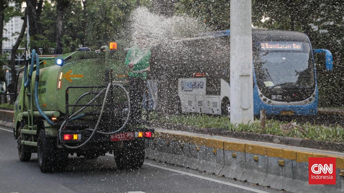 Sejumlah petugas menyemprot trotoar dan jalur hijau di kawasan Medan Merdeka dan Sudirman, Jakarta, Minggu (6/9). (CNN Indonesia/Febria Adha L).