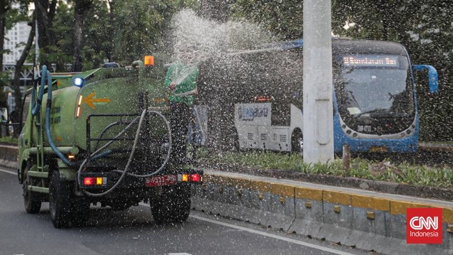 Sejumlah petugas menyemprot trotoar dan jalur hijau di kawasan Medan Merdeka dan Sudirman, Jakarta, Minggu (6/9). (CNN Indonesia/Febria Adha L).