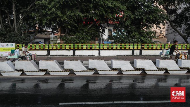 Sejumlah petugas menyemprot trotoar dan jalur hijau di kawasan Medan Merdeka dan Sudirman, Jakarta, Minggu (6/9). (CNN Indonesia/Febria Adha L).