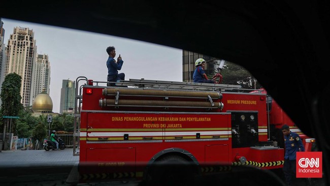 Sejumlah petugas menyemprot trotoar dan jalur hijau di kawasan Medan Merdeka dan Sudirman, Jakarta, Minggu (6/9). (CNN Indonesia/Febria Adha L).