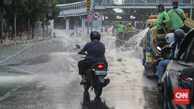 Sejumlah petugas menyemprot trotoar dan jalur hijau di kawasan Medan Merdeka dan Sudirman, Jakarta, Minggu (6/9). (CNN Indonesia/Febria Adha L)