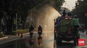 Sejumlah petugas menyemprot trotoar dan jalur hijau di kawasan Medan Merdeka dan Sudirman, Jakarta, Minggu (6/9). (CNN Indonesia/Febria Adha L)