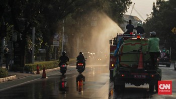 Sejumlah petugas menyemprot trotoar dan jalur hijau di kawasan Medan Merdeka dan Sudirman, Jakarta, Minggu (6/9). (CNN Indonesia/Febria Adha L)