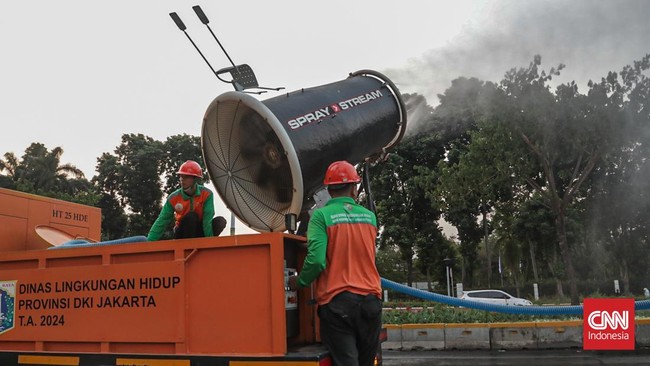 Sejumlah petugas menyemprot trotoar dan jalur hijau di kawasan Medan Merdeka dan Sudirman, Jakarta, Minggu (6/9). (CNN Indonesia/Febria Adha L)