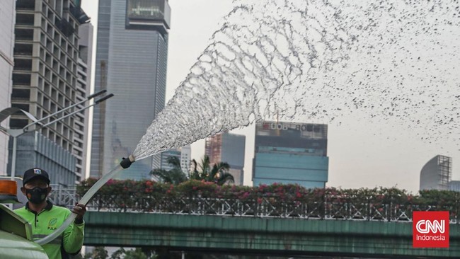 Sejumlah petugas menyemprot trotoar dan jalur hijau di kawasan Medan Merdeka dan Sudirman, Jakarta, Minggu (6/9). (CNN Indonesia/Febria Adha L)
