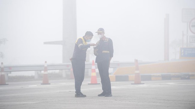 Petugas jalan tol berjaga di gerbang tol Palembang Jalan Tol Trans Sumatera (JTTS) ruas Palembang-Prabumulih yang tertutup kabut asap di Pemulutan, Kabupaten Ogan Ilir (OI), Sumatera Selatan, Minggu (6/9/2026). PT Hutama Karya (Persero) selaku pengel
