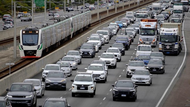 This picture shows a train heading toward Perth's central business district as cars commute alongside during the busy hours on March 23, 2026. Western Australia's government says there has been a big spike in the number of people using public transpo