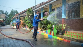 Petugas pemadam kebakaran menyemprotkan air untuk membersihkan lokasi dari abu vulkanik Gunung Anak Krakatau di SDN 1 Merak Belantung, Kalianda, Kabupaten Lampung Selatan, Lampung, Senin (7/9/2026). Pembersihan dilakukan untuk mencegah penumpukan abu