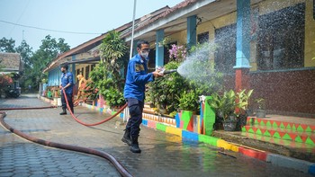 Petugas pemadam kebakaran menyemprotkan air untuk membersihkan lokasi dari abu vulkanik Gunung Anak Krakatau di SDN 1 Merak Belantung, Kalianda, Kabupaten Lampung Selatan, Lampung, Senin (7/9/2026). Pembersihan dilakukan untuk mencegah penumpukan abu