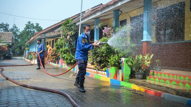 Petugas pemadam kebakaran menyemprotkan air untuk membersihkan lokasi dari abu vulkanik Gunung Anak Krakatau di SDN 1 Merak Belantung, Kalianda, Kabupaten Lampung Selatan, Lampung, Senin (7/9/2026). Pembersihan dilakukan untuk mencegah penumpukan abu