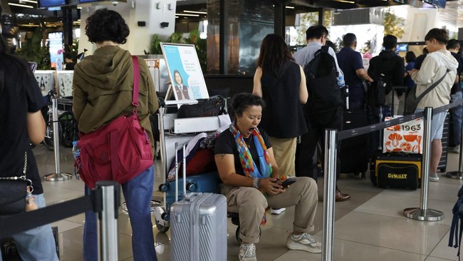 A stranded passenger sits on a luggage cart while in a customer service area at Soekarno-Hatta International Airport after the airport closed its operations due to the eruption of Mount Anak Krakatau, in Tangerang, near Jakarta, Indonesia, September