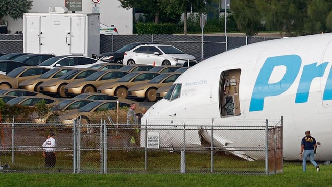 Tesla Cybercabs are parked in a lot next to where a crashed Amazon Prime Air cargo plane came to rest, where airport officials said it overran a runway at Miami International Airport, in Miami, Florida, U.S., September 6, 2026. REUTERS/Marco Bello
