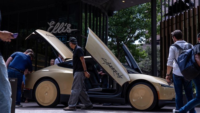 People examine a gold-colored Tesla Cybercab parked outside a bar in downtown ahead of an event in Austin, Texas, U.S. September 3, 2026.  REUTERS/Kaylee Greenlee