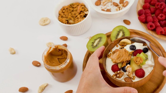 Rekomendasi camilan sore hari yang bisa menambah energi adalah greek yogurt dengan tambahan beri, almond, dan biji rami.