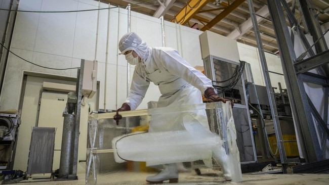 A worker handling a block of ice from machine at the Kuramoto Ice factory in Kanazawa, Ishikawa prefecture.