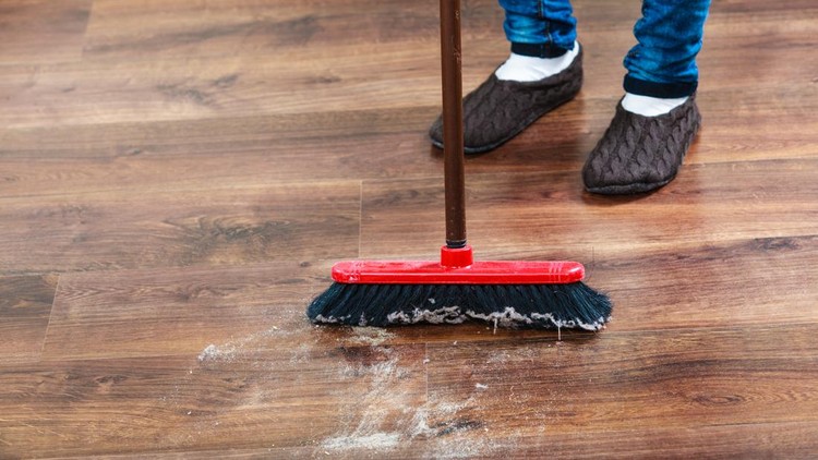 Cleanup housework concept&period; Closeup broom and female foots&period; Cleaning woman sweeping wooden floor&period;