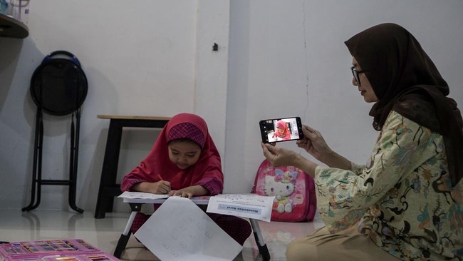 Orang tua merekam aktivitas anaknya yang mengikuti penerapan pembelajaran jarak jauh (PJJ) di Kota Pekanbaru, Riau, Rabu (9/9/2026). Pemerintah Kota Pekanbaru kembali menerapkan sistem pembelajaran jarak jauh bagi peserta didik tingkat PAUD hingga SM