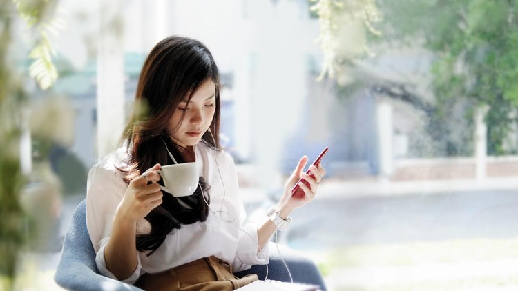 Shot of a beautiful asian woman listening to her music from her phone in a coffee shop&period;