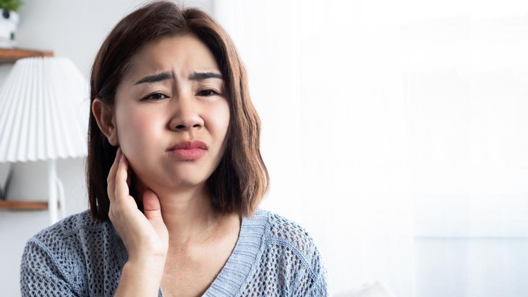 asian woman suffering from a toothache with swelling around her tooth&comma; gums&comma; jaw&comma; and inside mouth&comma; feeling pain possibly caused by gingivitis&comma; tooth decay&comma; gum infection&comma; abscess&comma; broken tooth