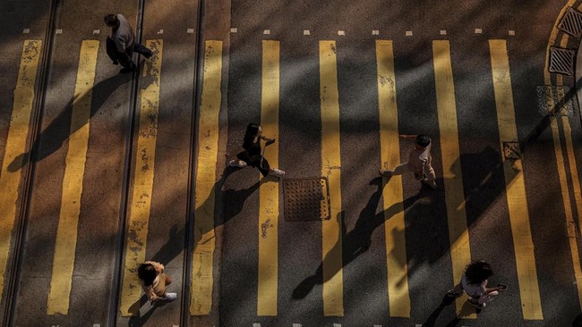 People cross a street in Hong Kong's Central district, China, July 24, 2026. REUTERS/Tyrone Siu