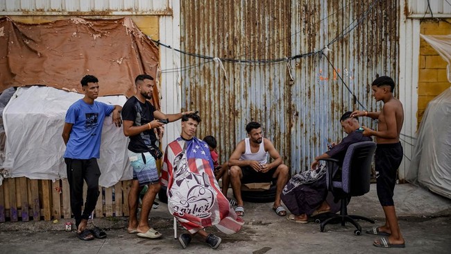 People get haircuts in the Tarajal complex, where many migrants are staying, following the mass crossing of thousands of migrants at the border with Morocco, in Ceuta, Spain, September 12, 2026. REUTERS/Ana Beltran
