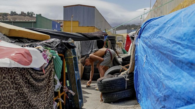 A person sweeps around their tent in the Tarajal complex following the mass crossing of thousands of migrants through the border with Morocco, in Ceuta, Spain, September 12, 2026. REUTERS/Ana Beltran