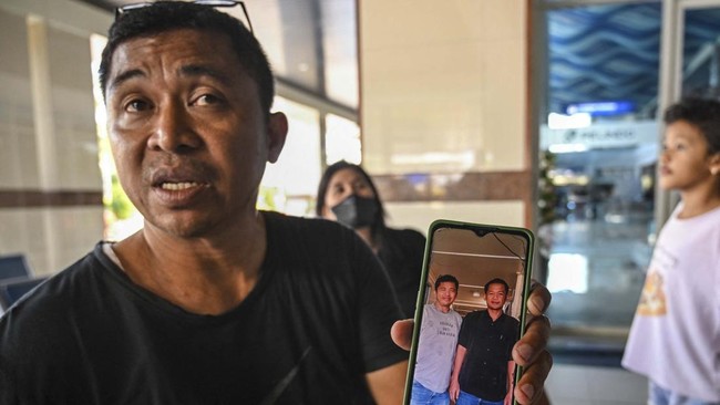 Fredy Manuhua shows a picture of his brother who was a passenger on Virgo Transport 8, carrying 243 people, which met with an accident en route from Surabaya, East Java to Banjarmasin, South Kalimantan, as relatives seek information about loved ones