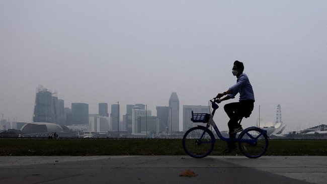 A cyclist wearing a protective mask rides along the bayfront with the city skyline shrouded in haze as smoke from regional forest fires reduces visibility across the island city-state, in Singapore, September 14, 2026. REUTERS/Suhaimi Abdullah