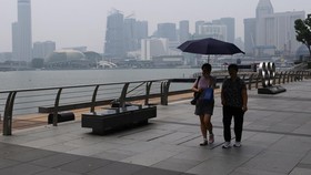 People walk along the bayfront with the city skyline shrouded in haze as smoke from regional forest fires reduces visibility across the island city-state, in Singapore, September 14, 2026. REUTERS/Suhaimi Abdullah