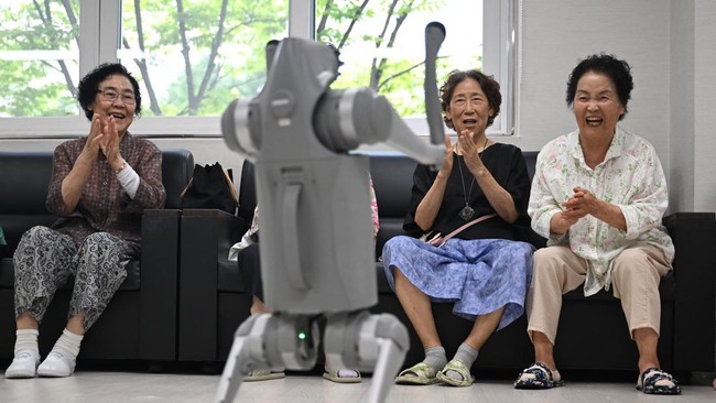 This picture taken on August 13, 2026 shows elderly people playing with a robot dog during a government-organised digital survival training at a senior community centre in Suwon. Age gaps in digital literacy are a global concern, yet the gulf has wid