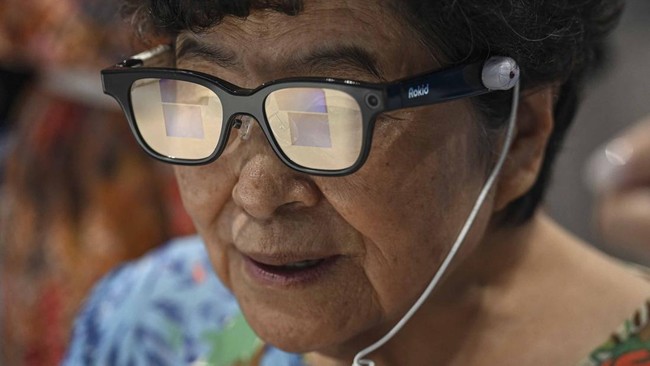 This photo taken on July 16, 2026 shows an elderly woman trying on a pair of Rokid AI glasses at Seoul Open City University in Seoul. Age gaps in digital literacy are a global concern, yet the gulf has widened massively in the hyper-connected and fas